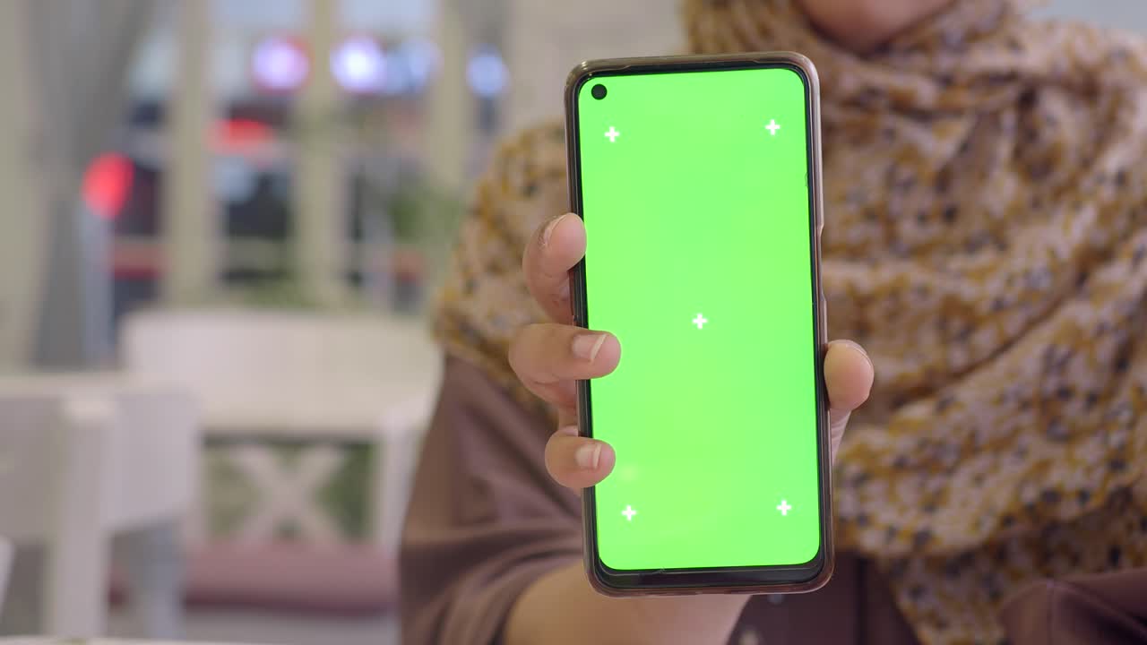 mujer sosteniendo un teléfono inteligente con una pantalla verde