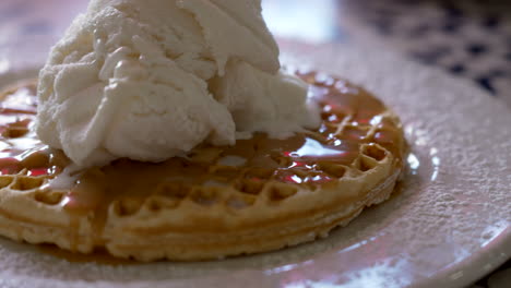 close up panning of baked belgian waffles with caramel sauce and vanilla ice cream in a plate