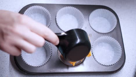 La-Mano-Femenina-Vierte-Masa-De-Cupcake-Amarilla-En-Una-Bandeja-De-Horno-De-Seis-Tazas-Para-Hornear