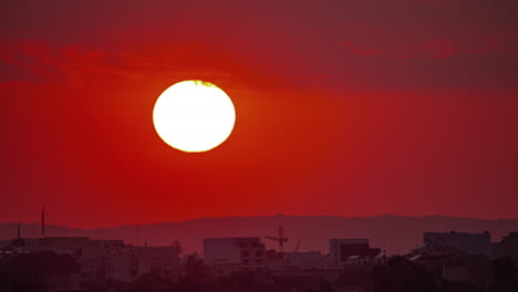 zoomado en la puesta de sol con un enorme sol brillante más allá de una aldea - lapso de tiempo