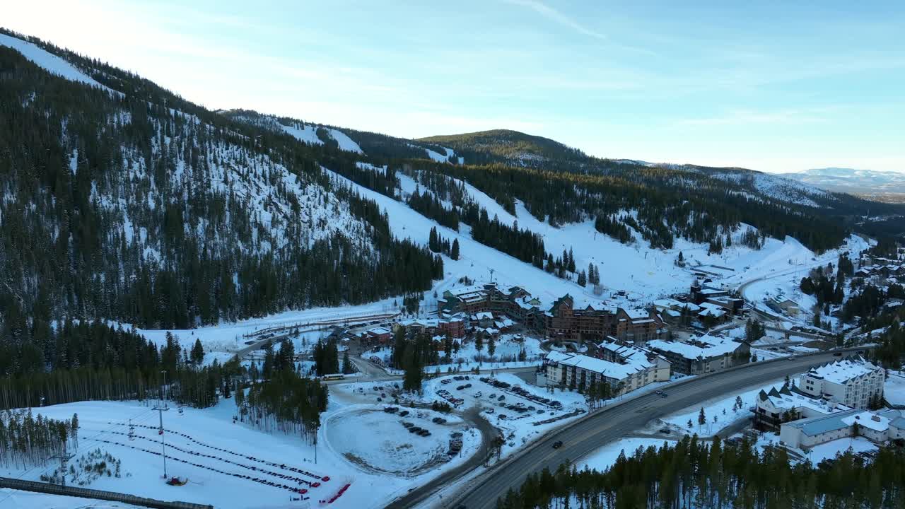 el sobrevuelo aéreo de drones del parque de invierno de la zona base de la estación de esquí de colorado con coches conduciendo por la carretera al atardecer en un día de invierno.