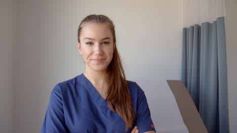 Portrait-Of-Female-Nurse-Wearing-Scrubs-In-Exam-Room