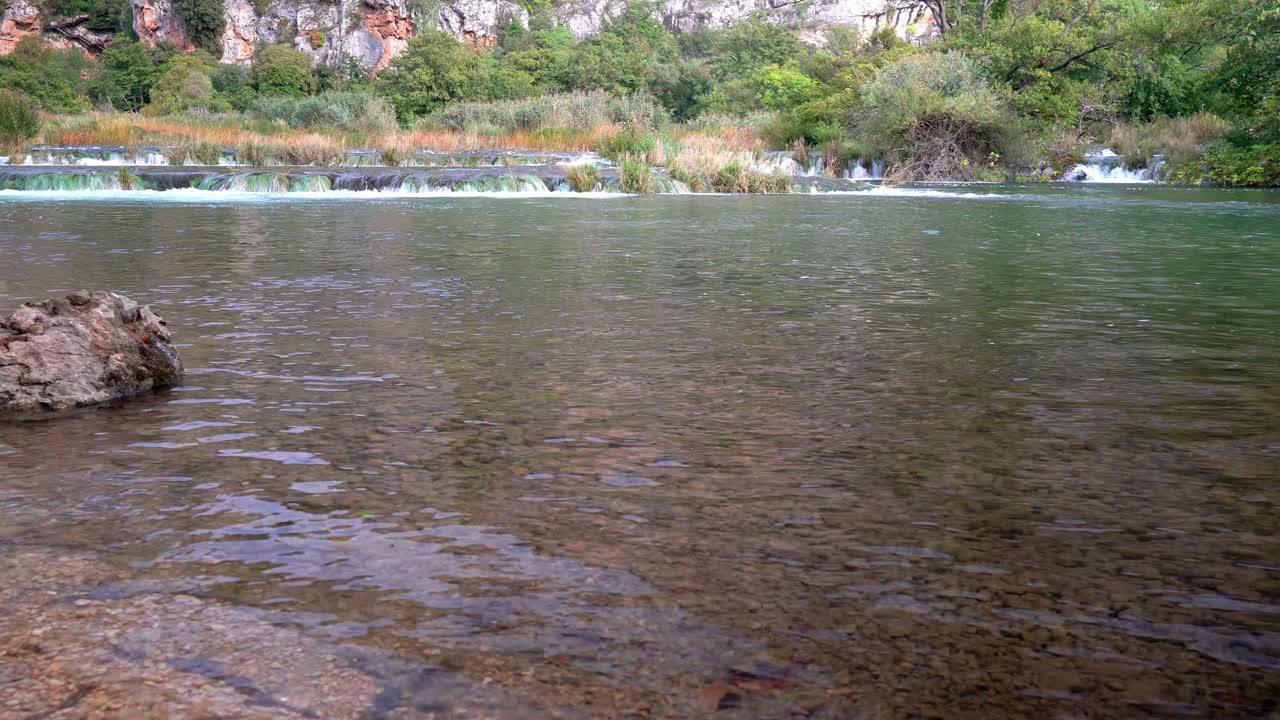 짧지만 넓고 강한 폭포는 한 연못에서 바위에 초점을 맞춘 크로아티아 크르카 국립공원의 다른 잠수 풀까지