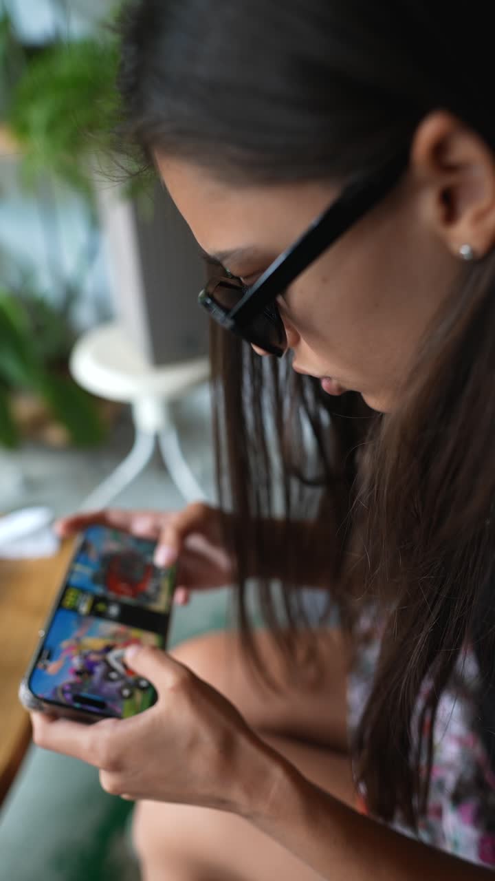 una mujer joven jugando a un juego móvil en un café.