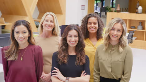 portrait of smiling multi-cultural female business team standing in modern open plan office