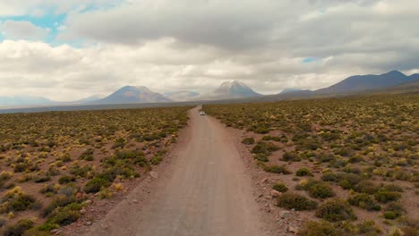 Aerial-cinematic-shot-distancing-a-lonely-car-in-a-dirt-road-in-the-Atacama-Desert,-Chile,-South-America