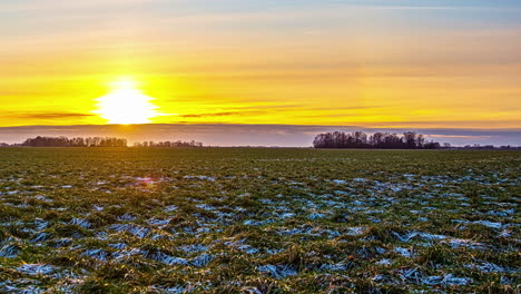 puesta de sol de la tarde de lapso de tiempo sobre la nieve que se derrite en campos de hierba