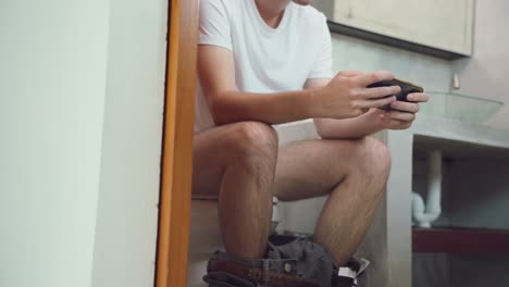 man using phone on toilet