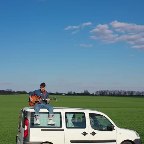 Man playing guitar on car. Young man sitting on car and playing guitar