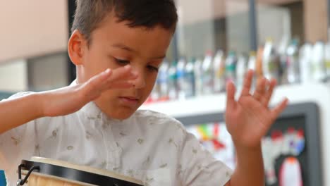 Vorderansicht-Eines-Aufmerksamen-Asiatischen-Schuljungen,-Der-In-Einem-Klassenzimmer-In-Der-Schule-Bongo-Spielt,-4k