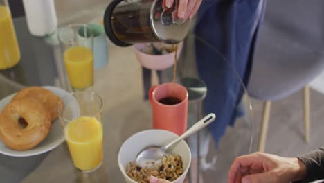 sección media de una mujer caucásica vertiendo café en una taza en casa