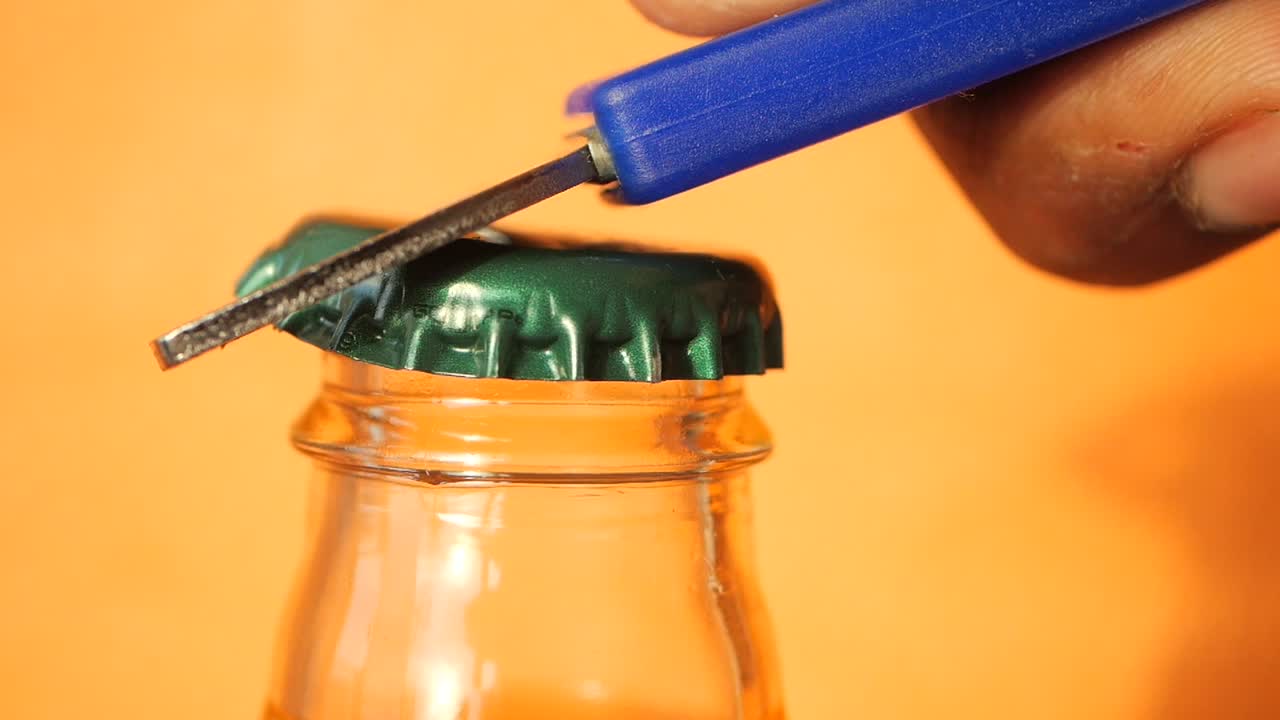 Hand opening a bottle cap with a bottle opener
