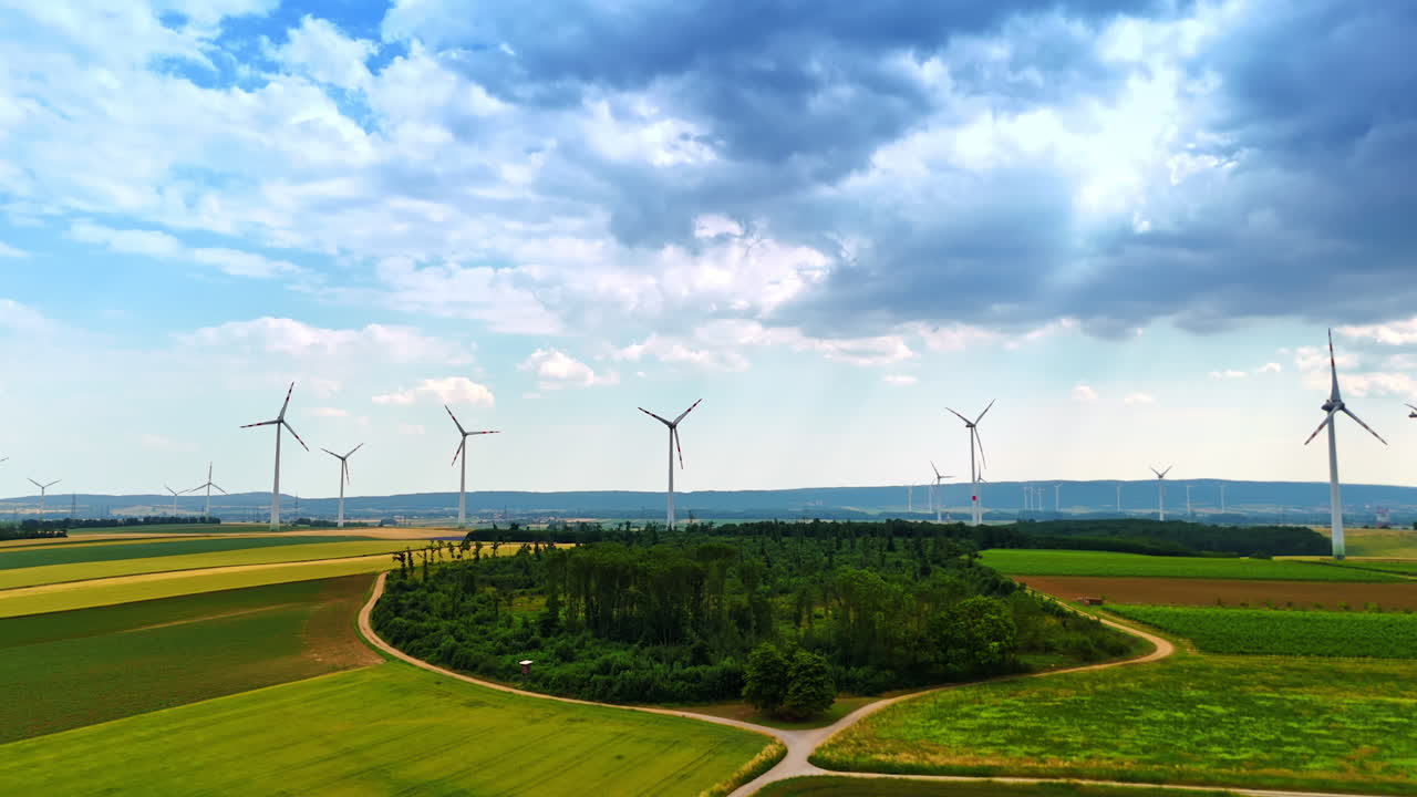 Wind turbines produce clean energy. Wind turbines are actively producing renewable energy amidst lush fields and dramatic skies in the countryside