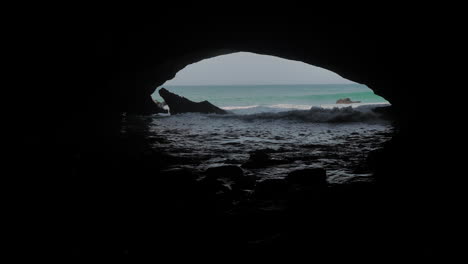 Toma-Panorámica-De-La-Cueva-Grande,-Olas-Rodando-Hacia-Ella,-Waenhuiskrans,-Sudáfrica