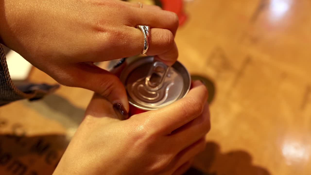 abriendo una lata de cola en las manos de la mesa