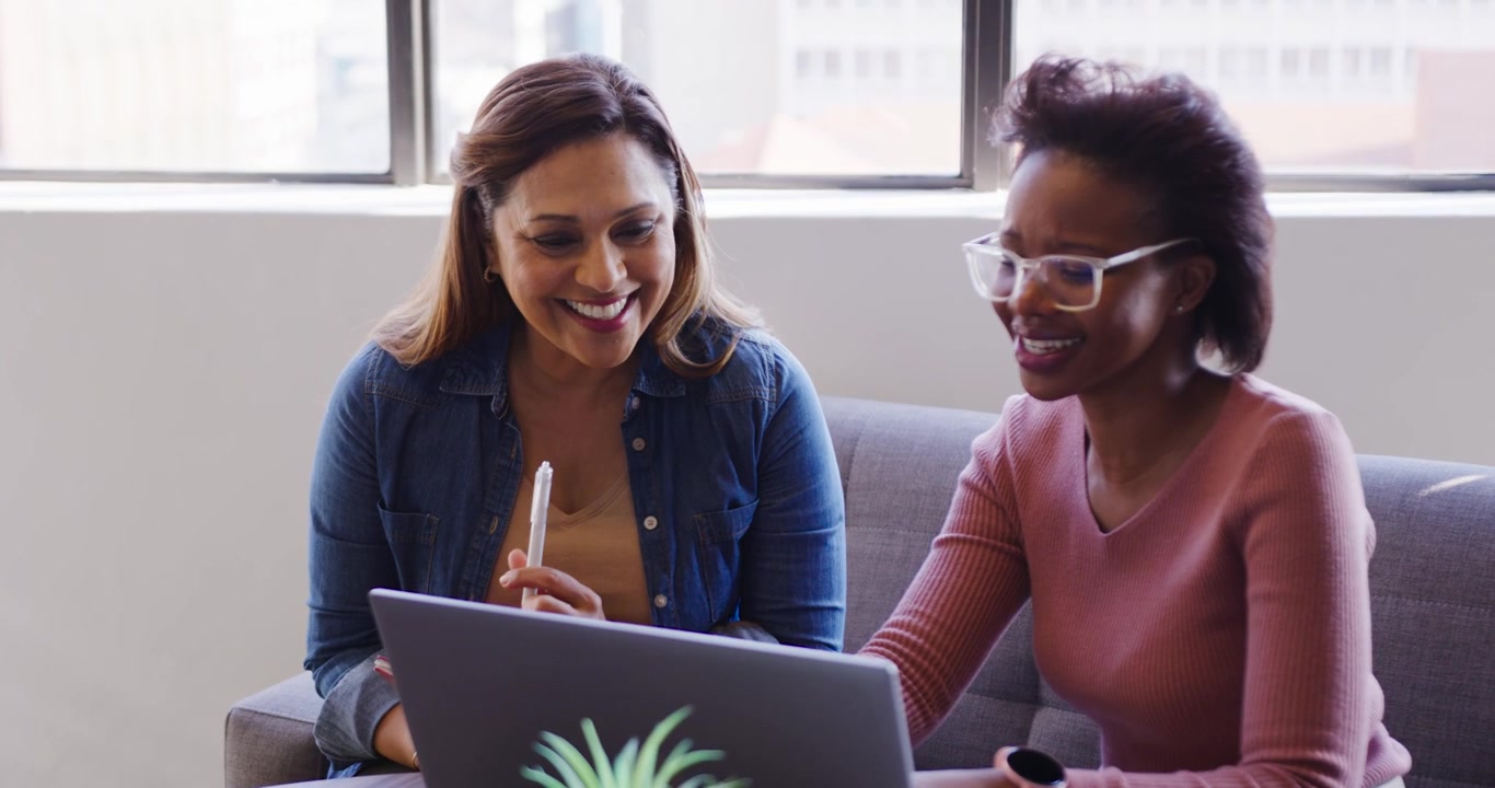 Colleghi afroamericani in denim e top rosa che sorridono al laptop, indicando, digitando e controllando gli appunti