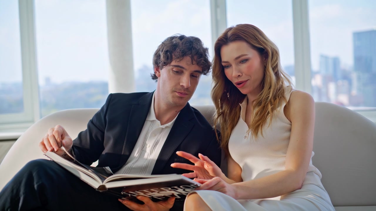 Couple choosing home interior design magazine luxury apartment sofa together.