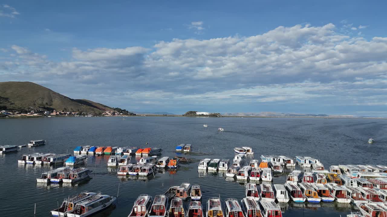 Aerial rises over boats moored in Puno, Peru harbour on Lake Titicaca