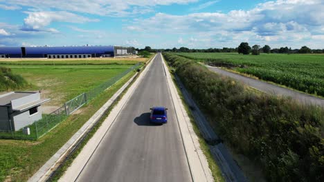 the blue car is driving the side road on a sunny day