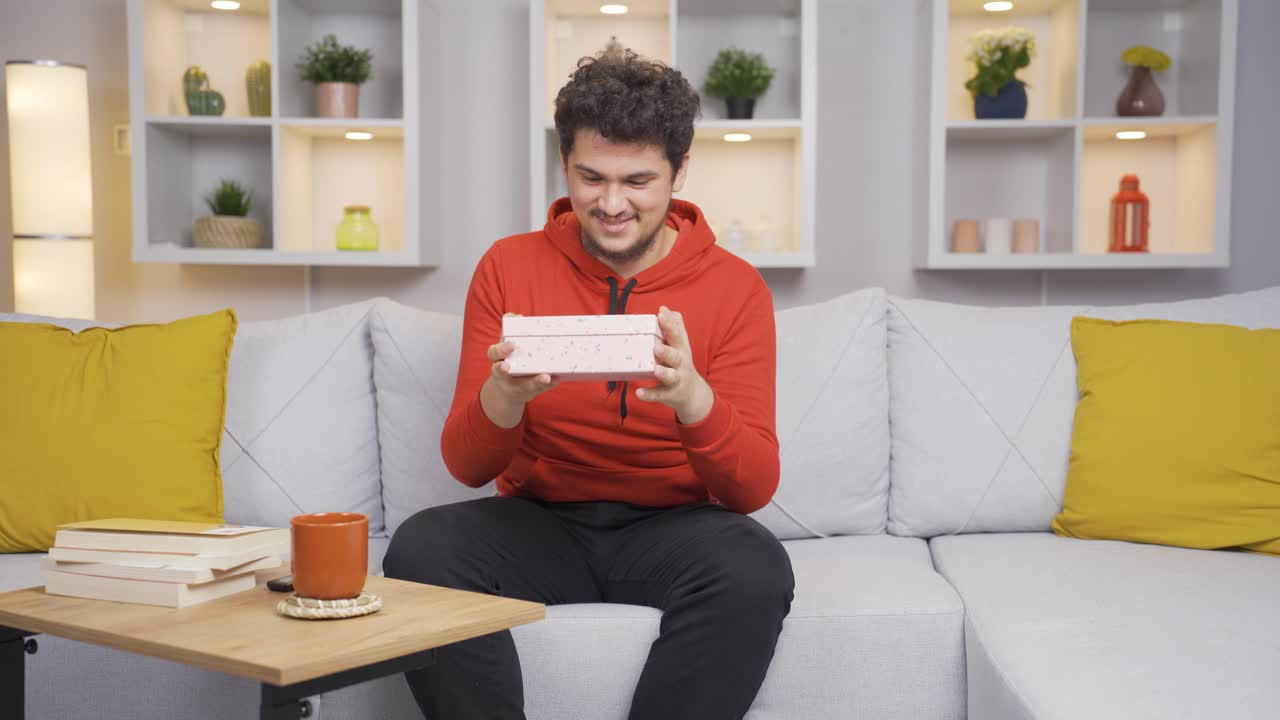 남자가 집에서 선물 상자를 열고 흥분하고 행복합니다.