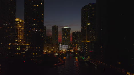 Amazing-footage-of-night-city.-Tall-apartment-or-office-buildings-along-river-against-colourful-sky-after-sunset.-Miami,-USA