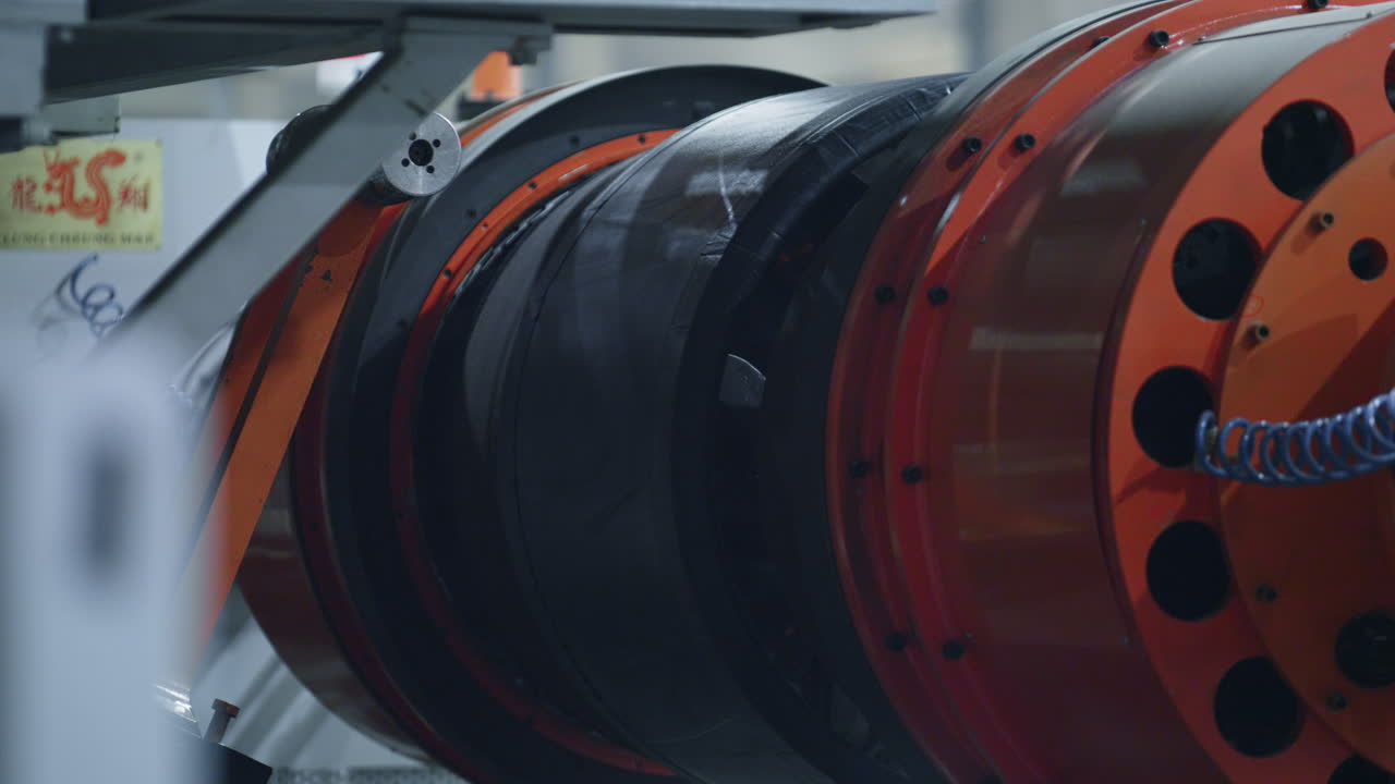 Detailed tyre production technology with modern orange machine moving in factory
