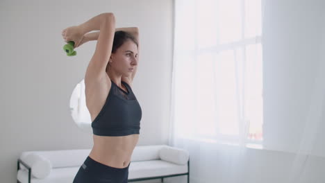 Exercises-for-triceps-muscles-on-the-hands-lifting-dumbbells-behind-the-head.-Young-woman-is-training-at-home.