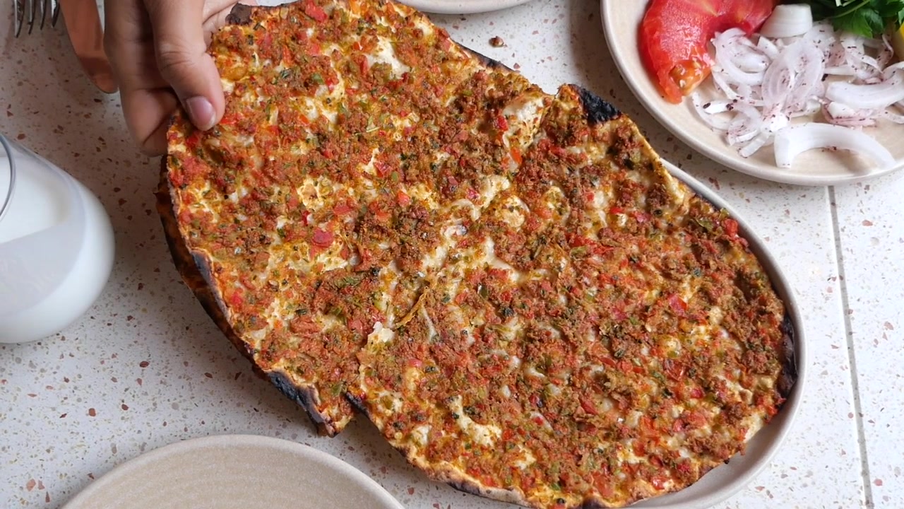 Geleneksel Türk lahmacunundan bir dilimi kaldıran el.