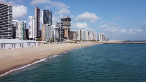 beautiful low-angle shot of forward movement with drone on the seafront of fortaleza, calm sea, calm waves, green water