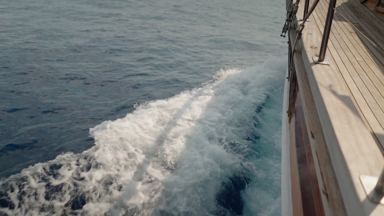 슬로우 모션:아름다운 목선 범선이 푸른 물에서 활 웨이크를 생성합니다.