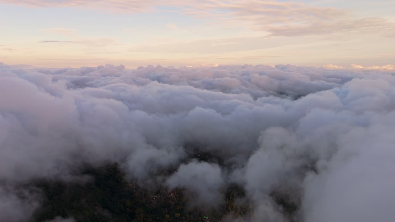 Cinematic flight above a dense sea of clouds featuring soft pink and purple hues. A majestic sunrise cloudscape over the highlands of Marilog District, Davao, creating a heavenly atmosphere