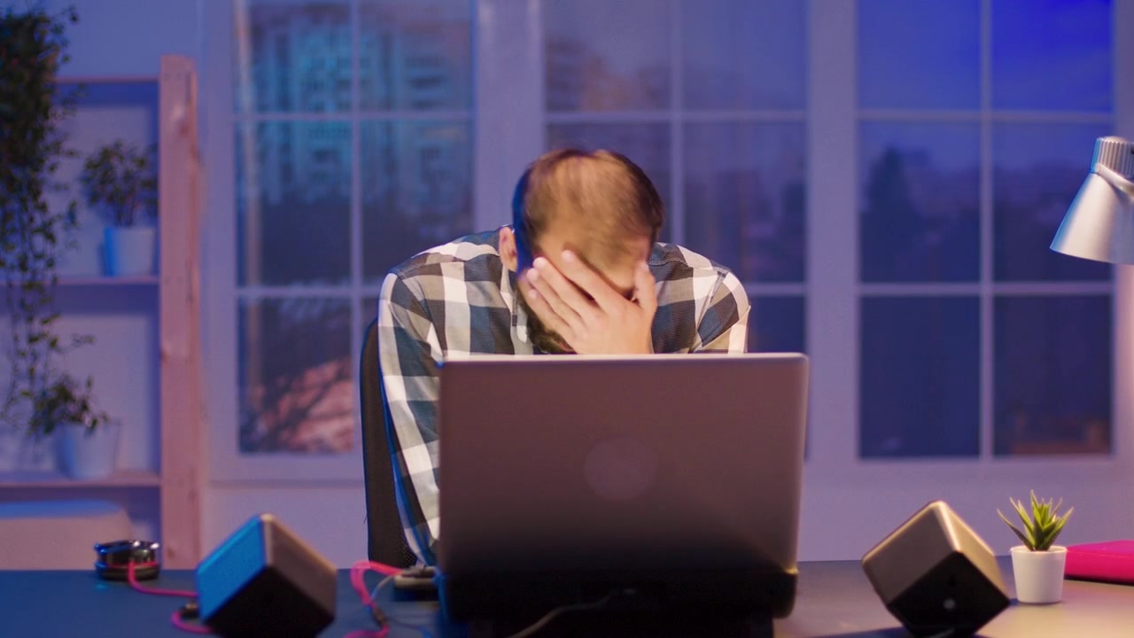 Tired Man Working Late on Laptop in Home Office