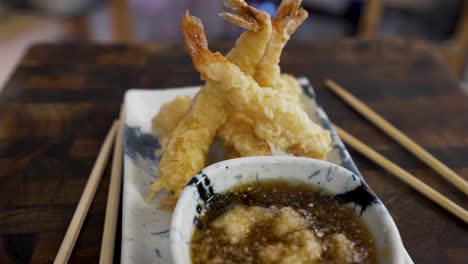 tempura-shrimp-with-traditional-tempura-dipping-sauce-on-white-blue-plate-and-wooden-background-spinning,-Japanese-food