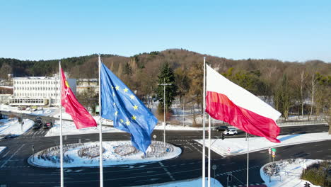 banderas de polonia, gdansk y la unión europea ondeando en el viento con la rotonda al fondo