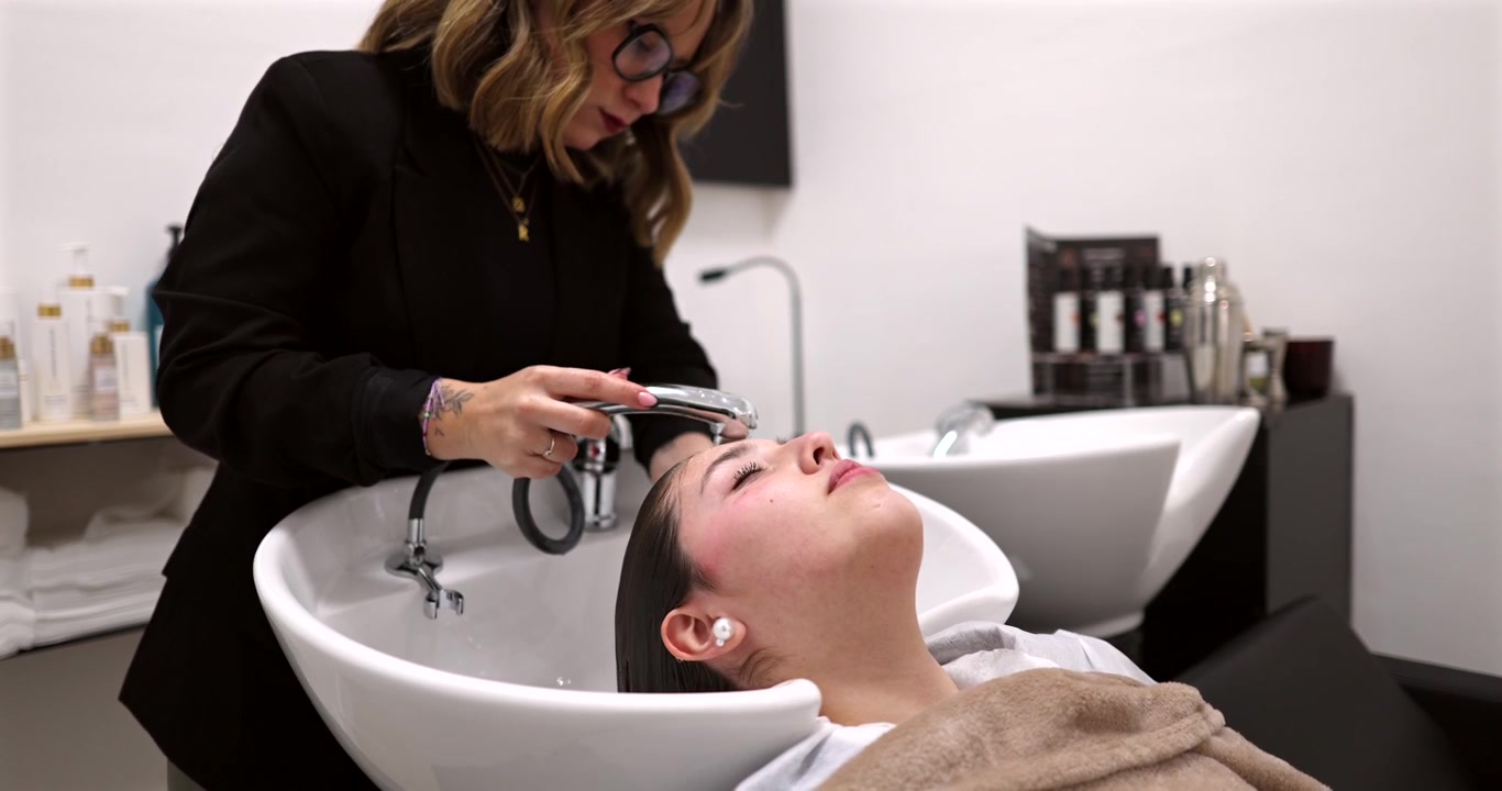 Parrucchiere che lava i capelli della cliente in un salone professionale