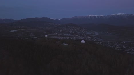 vista aérea de un valle al crepúsculo con antenas radar en la cima de una colina