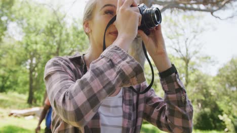 happy diverse couple walking and taking photos in park, slow motion