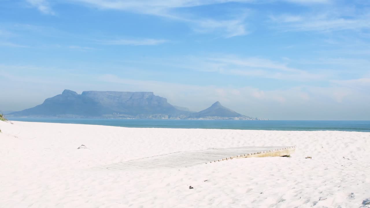 A tourist walks to the edge of a boardwalk to look at the scenic splendour of Table Mountain on a perfect Cape Town morning.