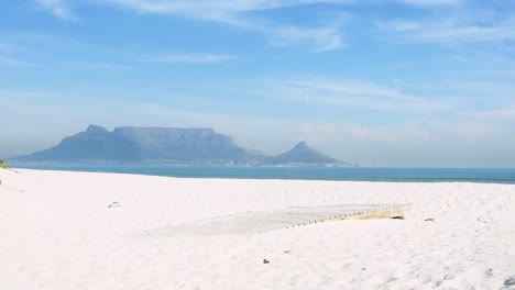 a tourist walks to the edge of a boardwalk to look at the scenic splendour of table mountain on a perfect cape town morning.