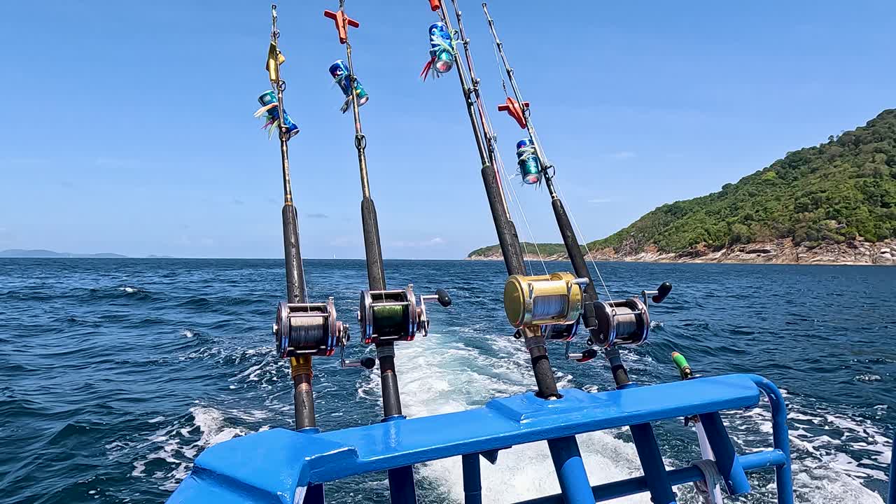 A boat navigates the waters near Phuket, Thailand, with fishing rods ready for action under clear skies