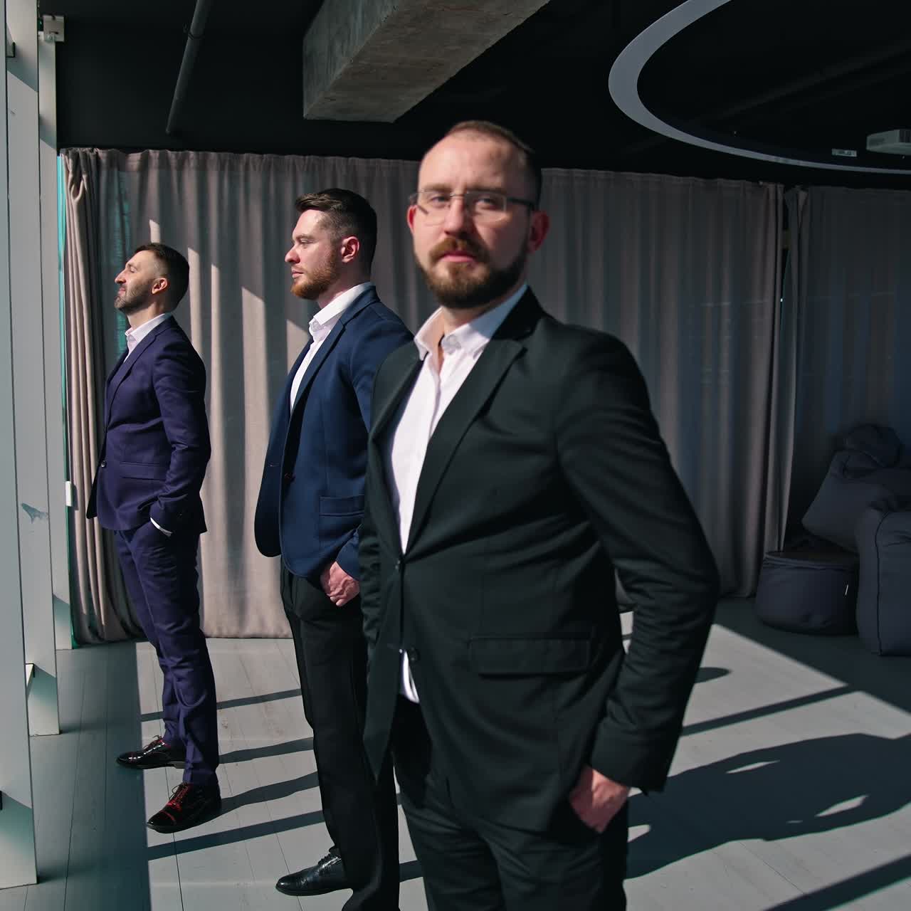 Businessmen looking out of large office window. Back full-length portraits of three entrepreneurs in costumes standing by the window in a office at daytime. Rear view