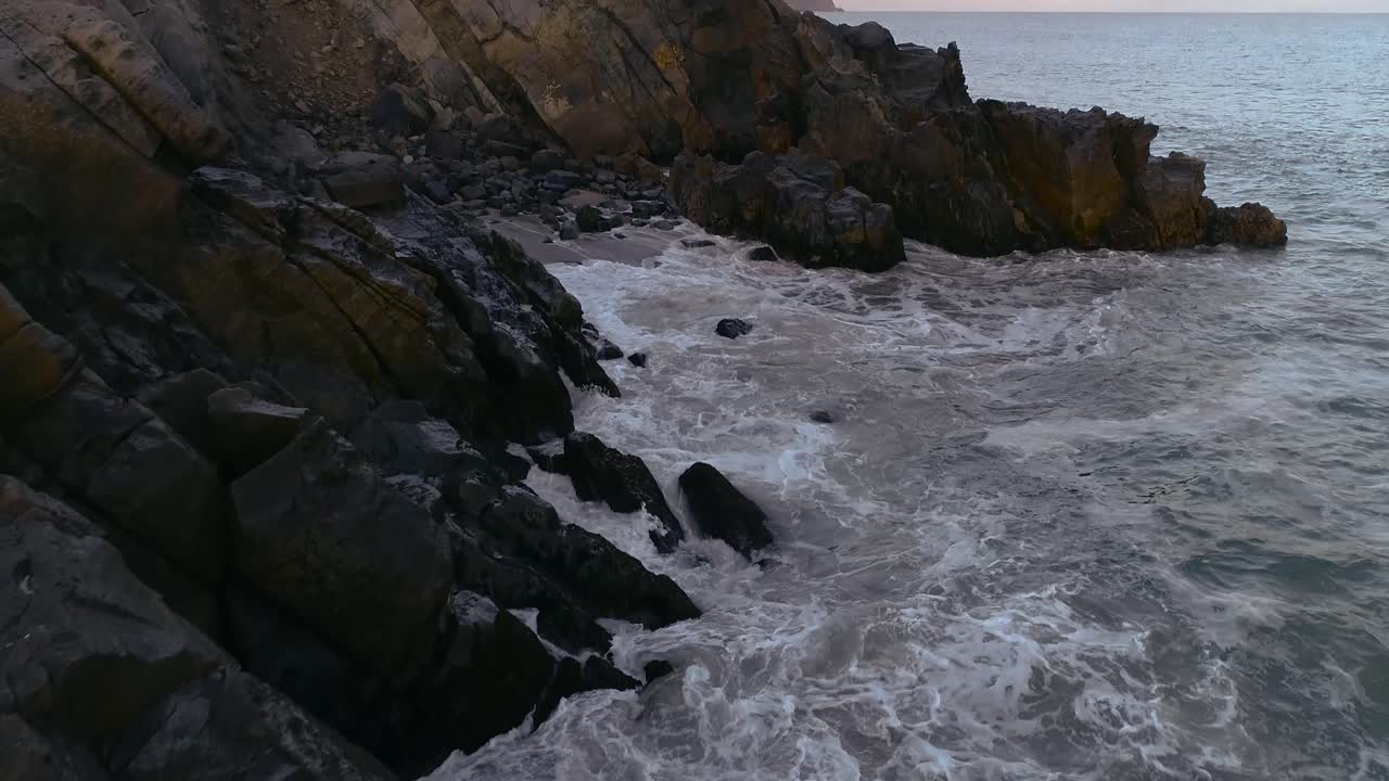 Onde oceaniche che si infrangono sugli scogli al tramonto