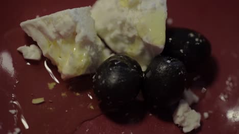 aceite de oliva rociado sobre queso feta y aceitunas negras