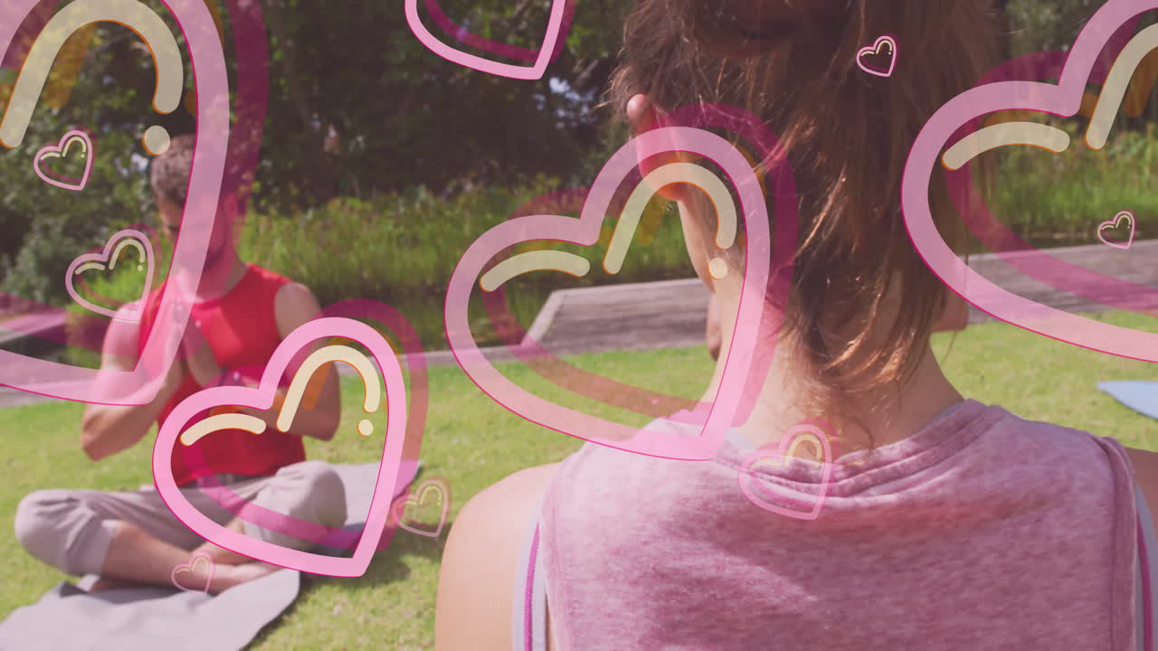 Practicing yoga outdoors, two people with animation of hearts around them