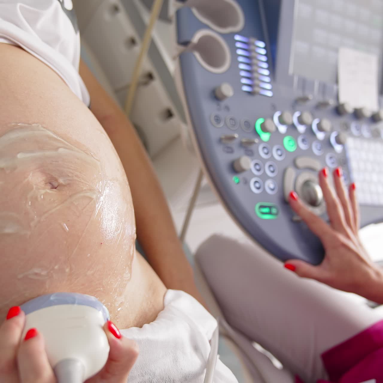 Hamile bir kadının ultrason sırasındaki karnı. Kadın doktor, modern tıbbi ekipmanla hamile bir kadına ultrason prosedürü uyguluyor. Yakın çekim.