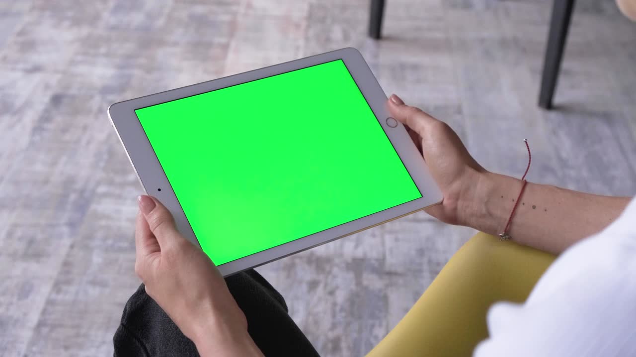 вид через плечо на планшетном устройстве в руках кавказской женщины. женщина держит компьютер с зеленым экраном. ключ хромы. нажатие, увеличение, прокрутка с отслеживанием движения.