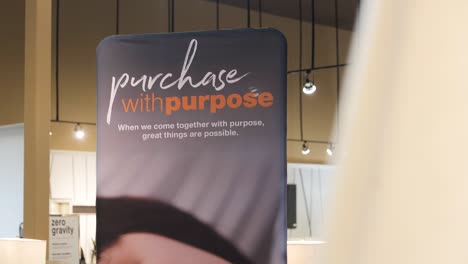 a 4k panning shot of a retail furniture store location financing promotional banner financing credit card sign 'purchase with purpose' orange and blue advertisement background with hanging lights