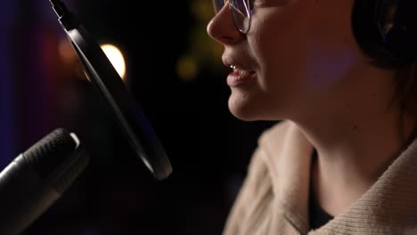 mujer cantando en un micrófono en un estudio de grabación
