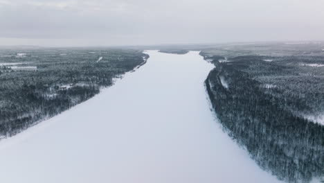 Luftaufnahme-Des-Zugefrorenen-Flusses-Und-Des-Verschneiten-Waldes-In-Lappland,-Finnland