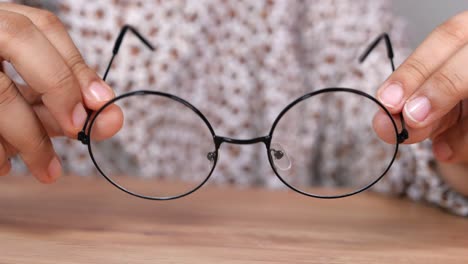 person adjusting round black eyeglasses